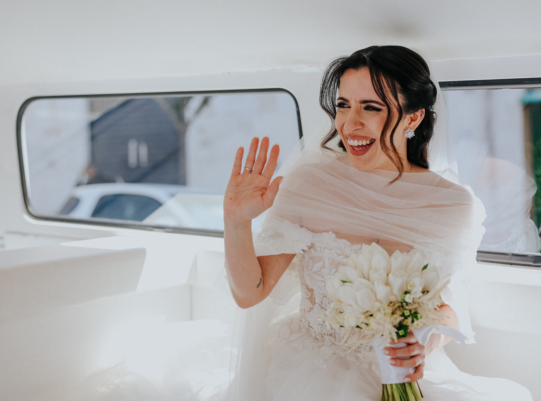 La sposa saluta ridendo dal furgoncino bianco prima della cerimonia