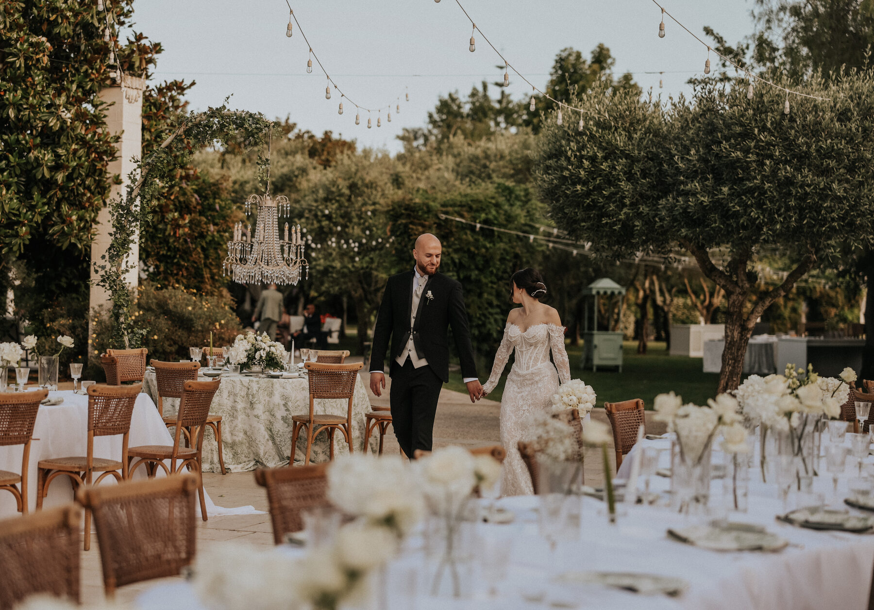 Sposi tra i tavoli del ricevimento in giardino