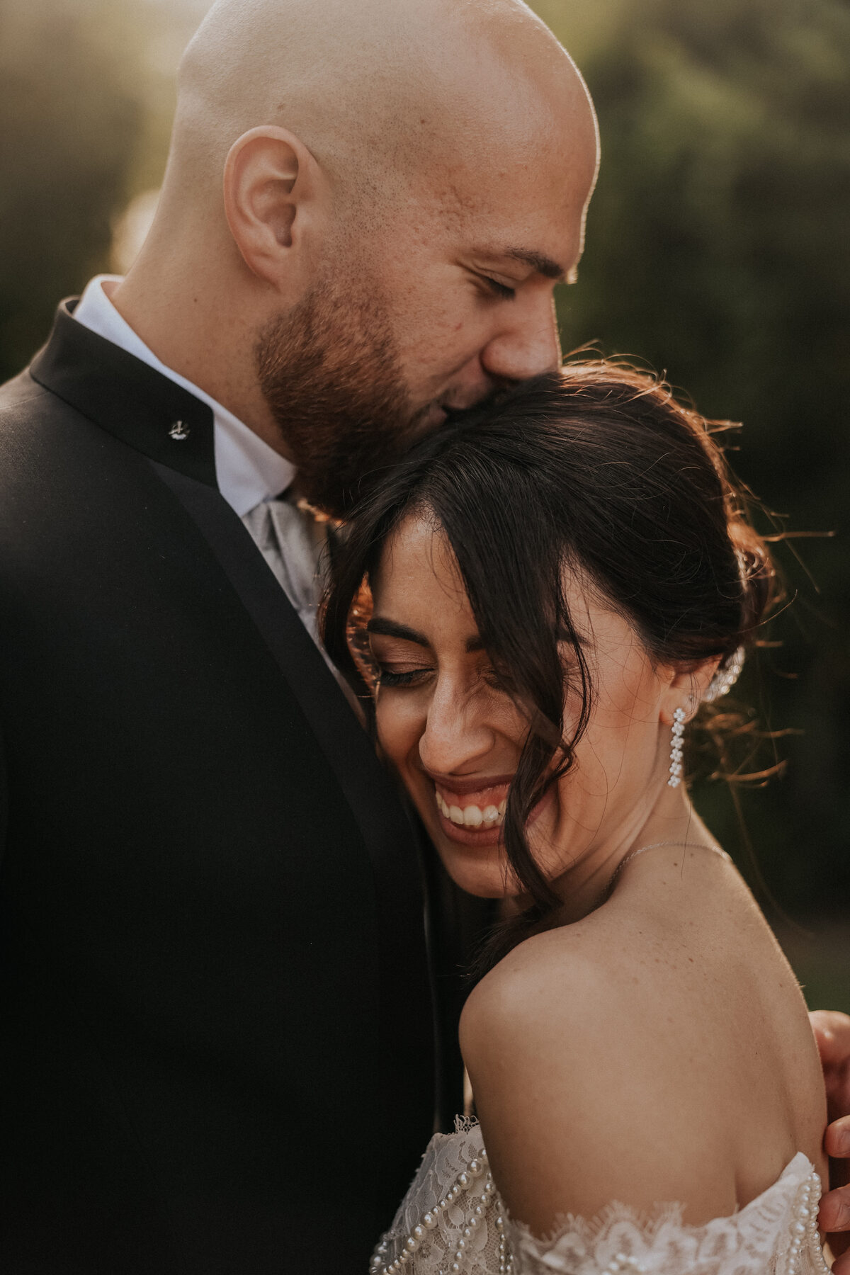 Risata di una sposa abbracciata allo sposo nella luce dorata
