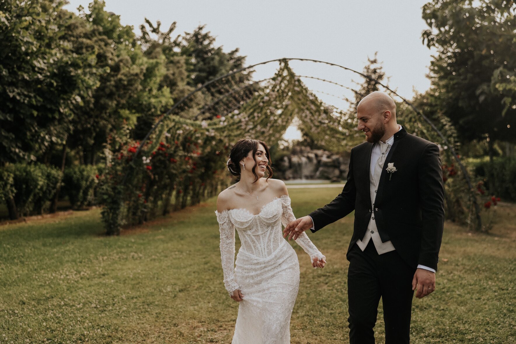 Sposi che camminano nel giardino della villa sotto gli archi fioriti